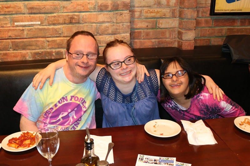 three individuals with Down syndrome at a restaurant
