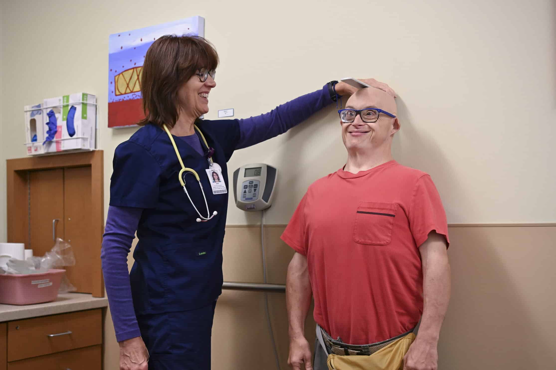 Nurse measuring the height of an older man with Down syndrome